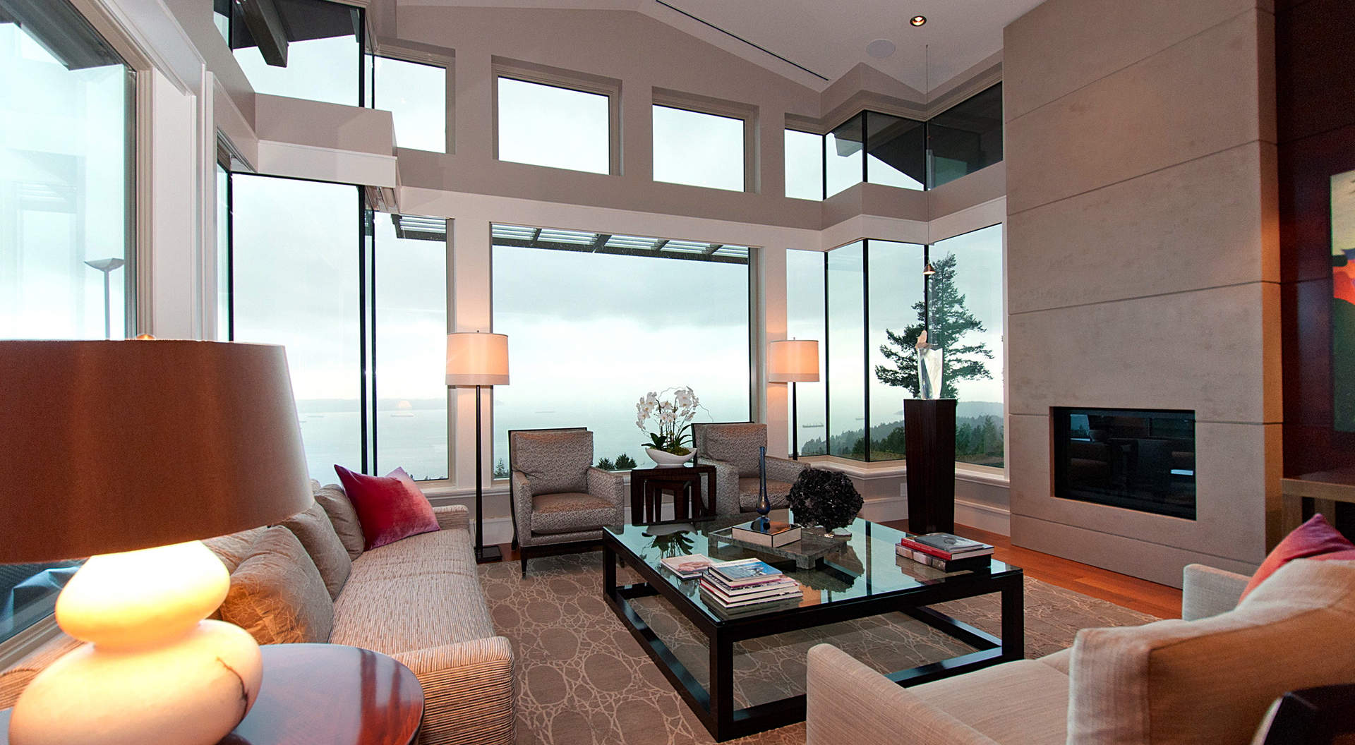 exciting-open-living-room-in-west-coast-penthouse-with-fancy-drum-lamp-shade-and-terrific-glass-coffee-table-and-sophisticated-sea-view-from-large-glass-windows